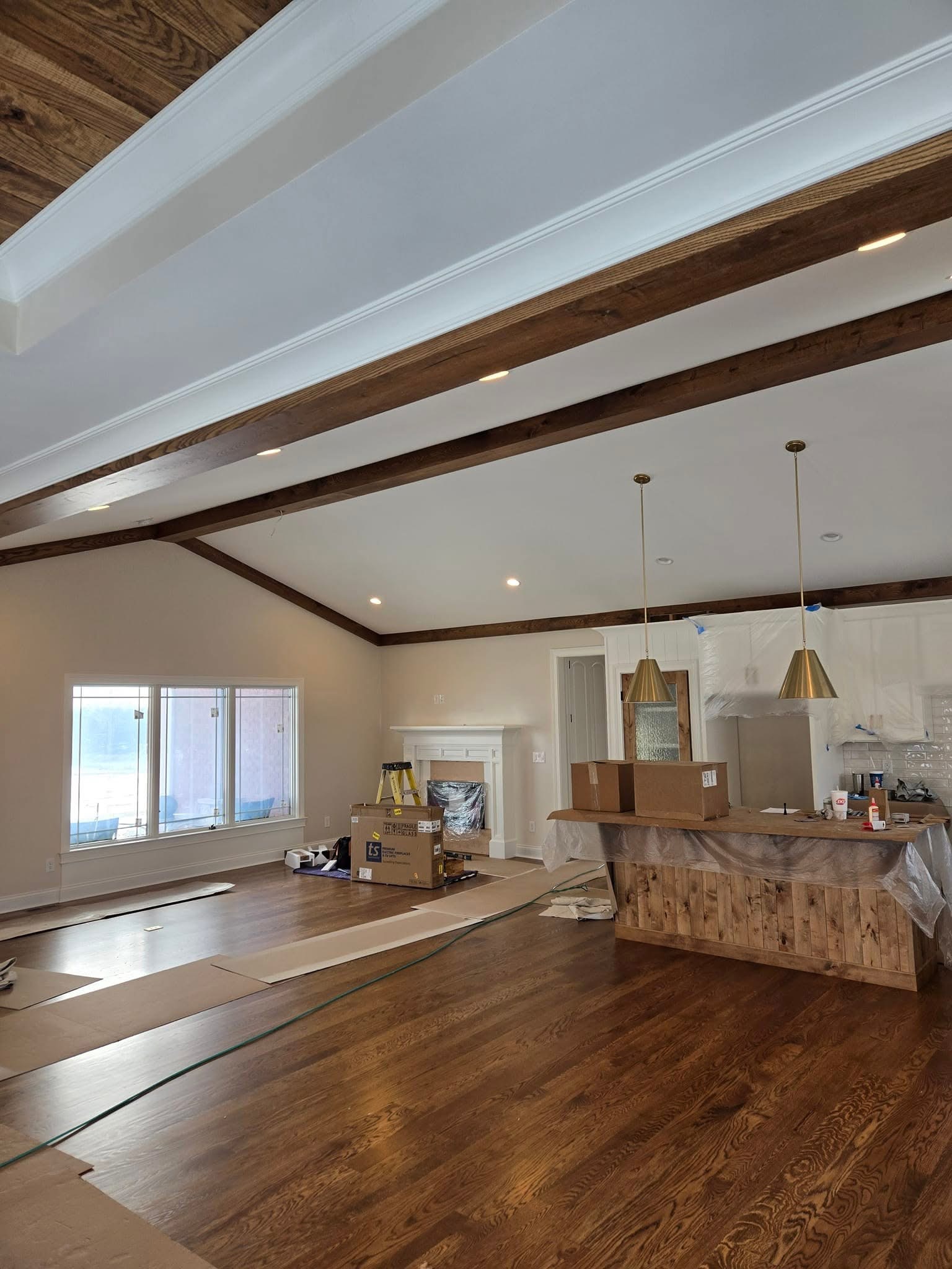 Dark wood ceiling beams and white trim in an open kitchen and living area.